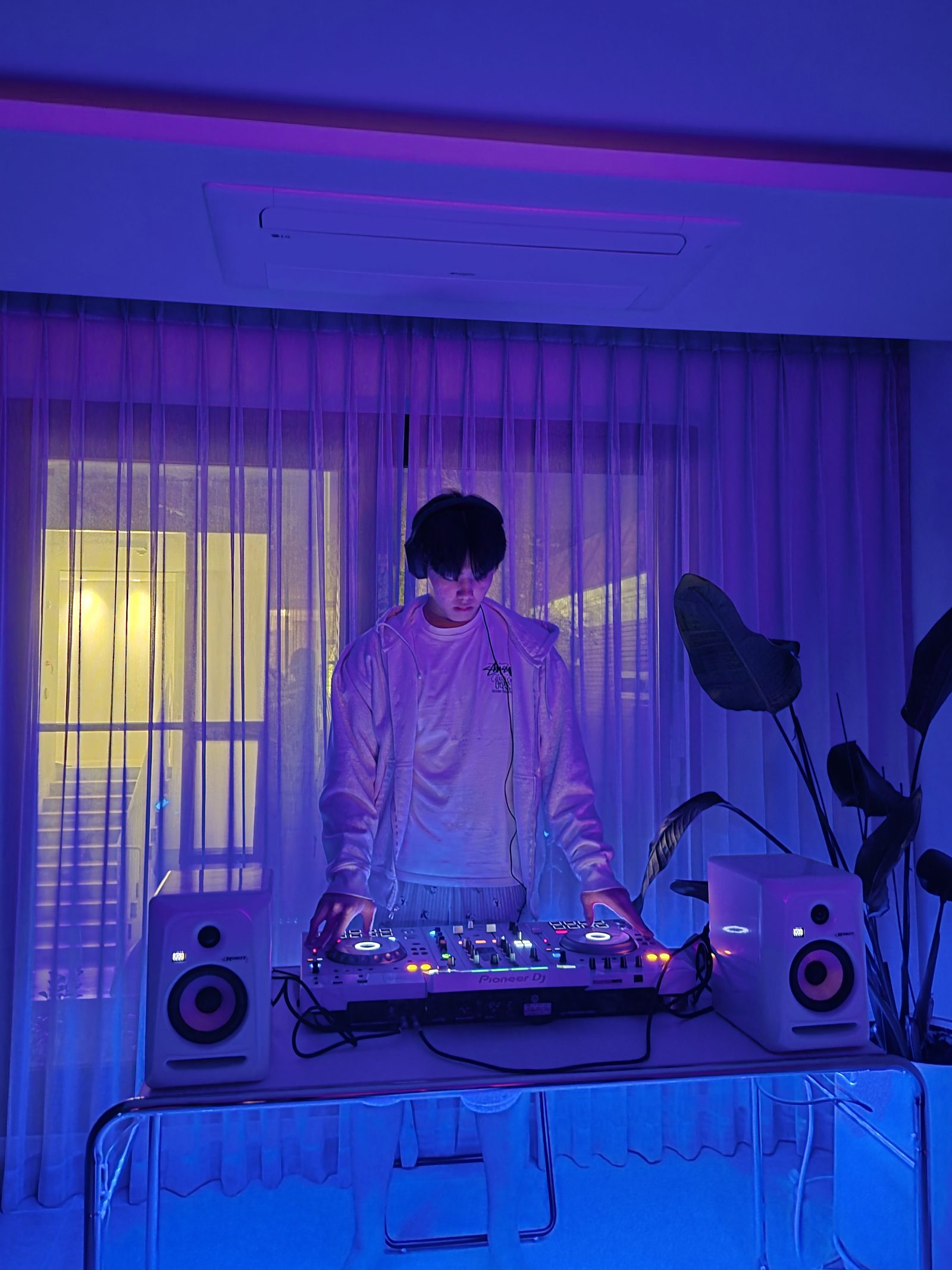 Me at home again, mixing on the same white controller, with more of the table and the floor visible.
